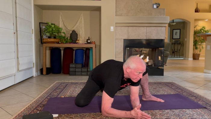 A man in yoga position, half kneeling and body bent forward