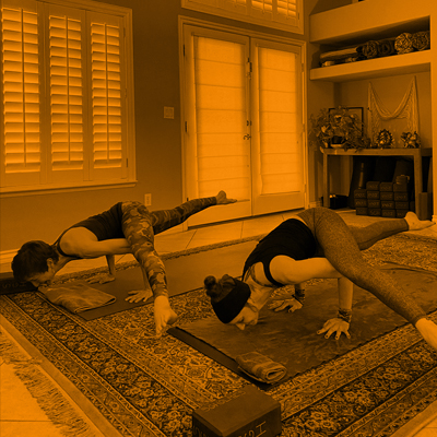 Two female in a yoga pose with the arms balancing the entire body and legs stretched on air